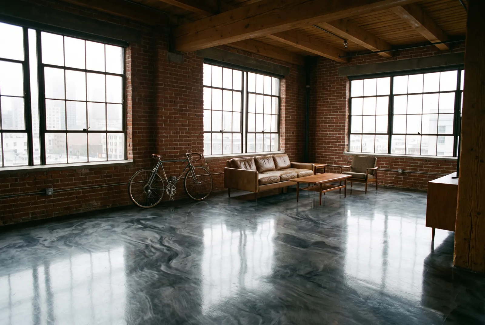 Charcoal and silver metallic epoxy floor in a brick warehouse loft with tall steel windows